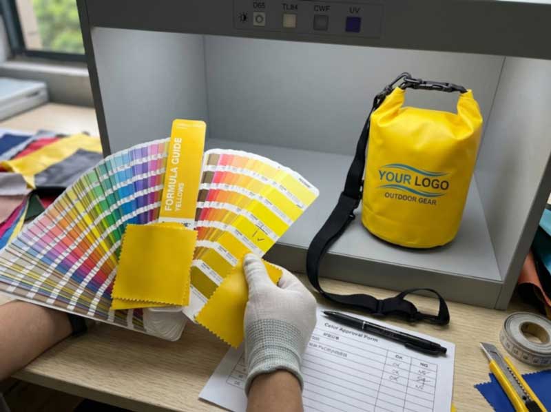 Pantone colour guide open beside fabric swatches and a printed sample bag